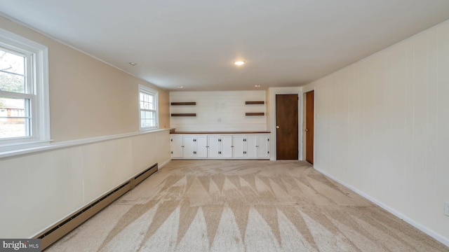 unfurnished room with baseboard heating and light carpet