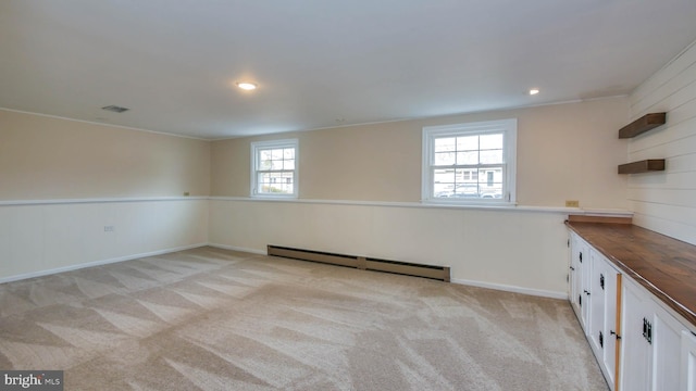 basement featuring visible vents, a baseboard heating unit, baseboards, light carpet, and recessed lighting