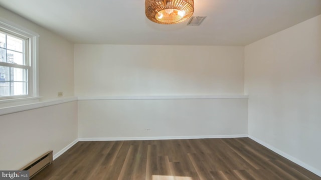 spare room with dark wood-type flooring, baseboards, visible vents, and a baseboard radiator