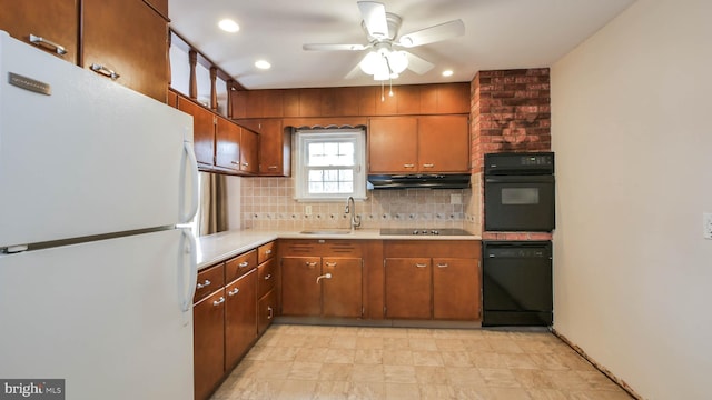 kitchen featuring black appliances, under cabinet range hood, a sink, light countertops, and decorative backsplash