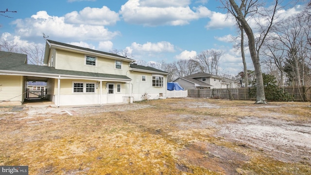 rear view of house with an attached carport and fence