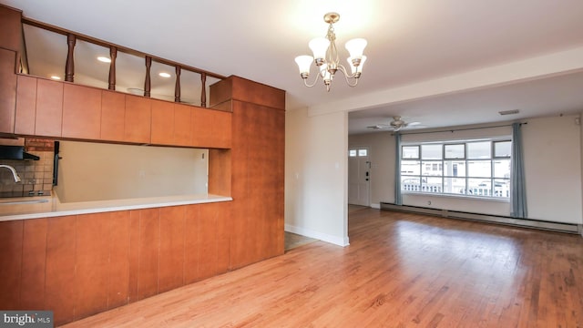 interior space with ceiling fan with notable chandelier, light wood-type flooring, baseboard heating, and a sink