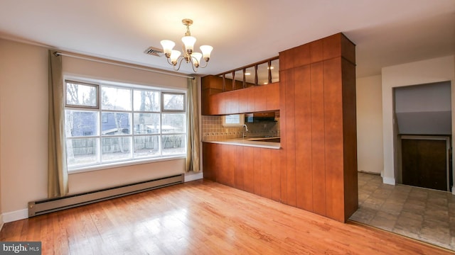 kitchen with baseboard heating, modern cabinets, wood finished floors, and brown cabinetry