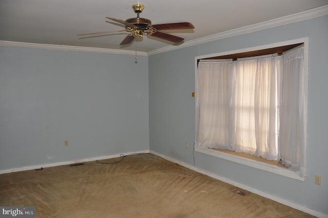 empty room with baseboards, carpet flooring, a ceiling fan, and crown molding