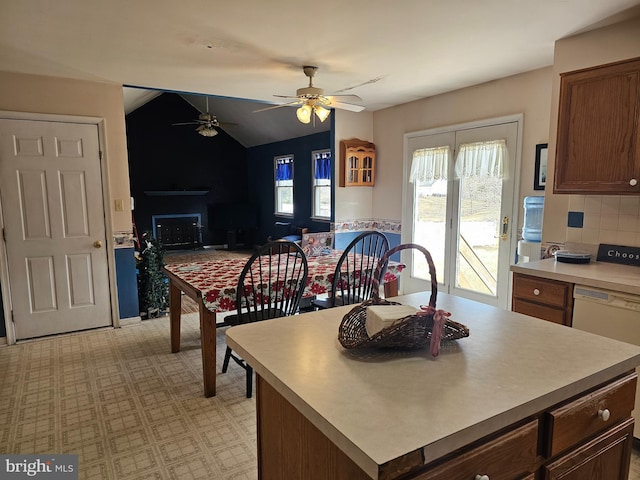 kitchen featuring white dishwasher, a kitchen island, vaulted ceiling, light countertops, and backsplash