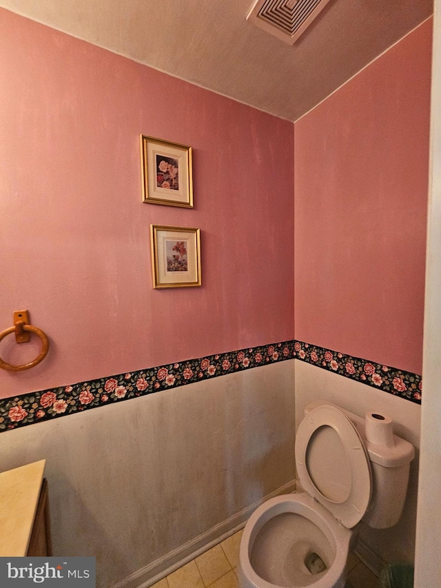 half bathroom with toilet, visible vents, and tile patterned floors