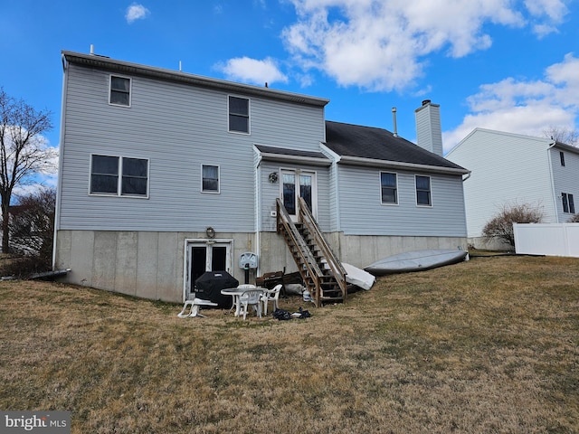 rear view of property with french doors, a lawn, a chimney, and fence