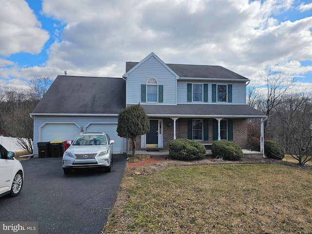 traditional home with a porch, an attached garage, brick siding, driveway, and a front lawn