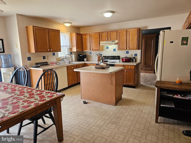 kitchen with white appliances, tasteful backsplash, a kitchen island, light countertops, and under cabinet range hood