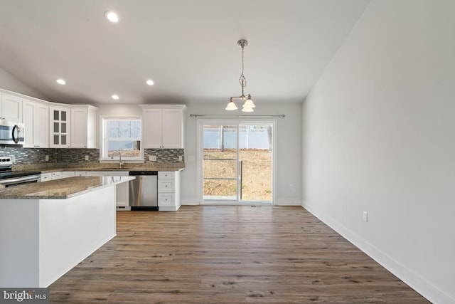 kitchen featuring appliances with stainless steel finishes, a healthy amount of sunlight, white cabinets, and tasteful backsplash