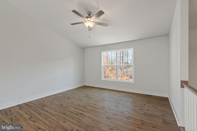 spare room with a ceiling fan, visible vents, baseboards, and wood finished floors