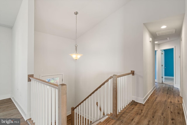 hallway featuring visible vents, wood finished floors, an upstairs landing, and baseboards