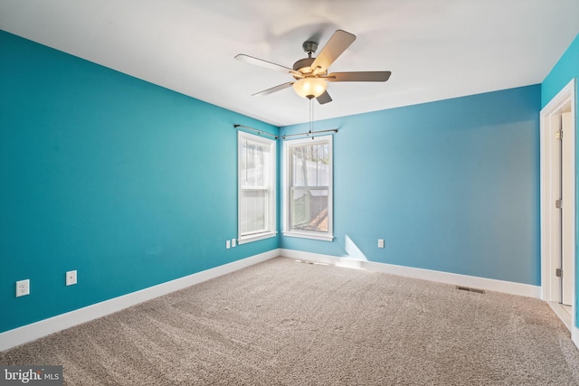 spare room with a ceiling fan, carpet, visible vents, and baseboards