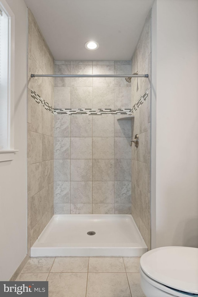 full bath featuring a stall shower, toilet, and tile patterned floors