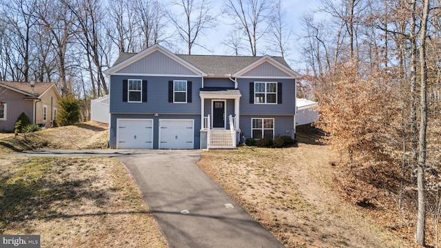 split foyer home with a shingled roof, driveway, and an attached garage