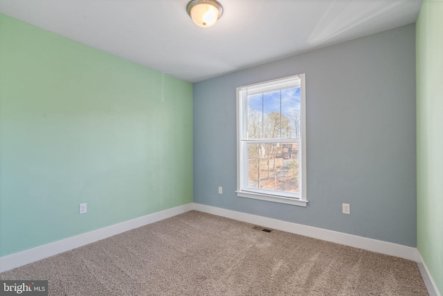 spare room featuring carpet flooring, visible vents, and baseboards