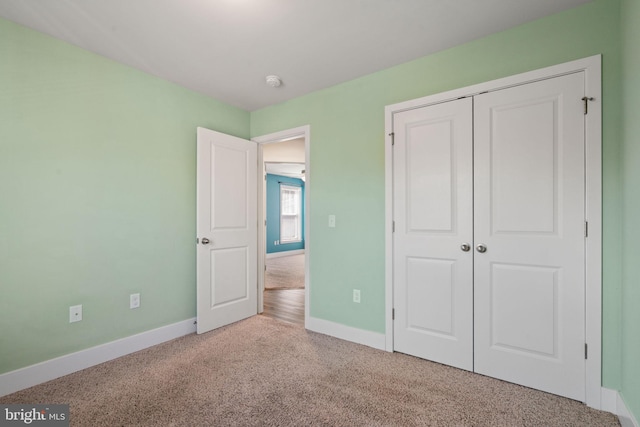 unfurnished bedroom with carpet floors, a closet, and baseboards