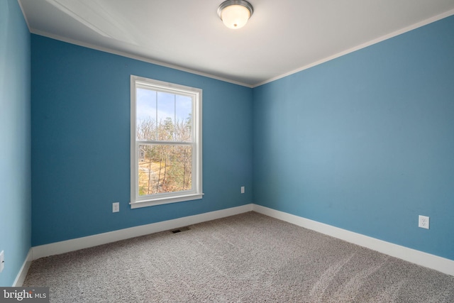 spare room with carpet floors, baseboards, visible vents, and crown molding