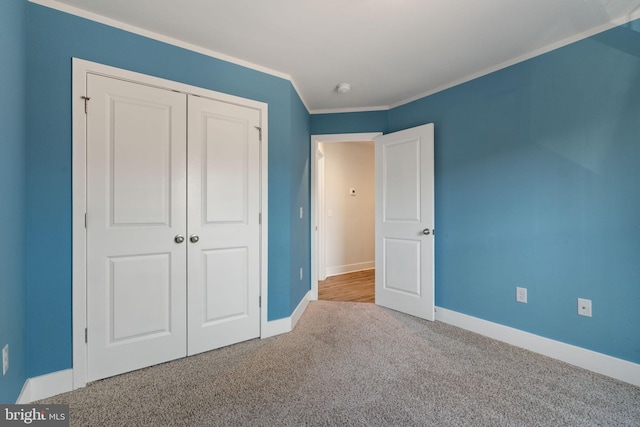 unfurnished bedroom featuring baseboards, carpet floors, a closet, and crown molding