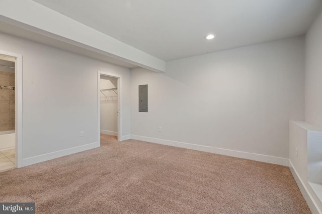 spare room featuring baseboards, electric panel, and light colored carpet