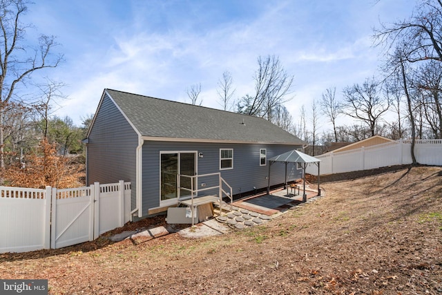 back of property featuring a shingled roof, a gate, a fenced backyard, and a patio