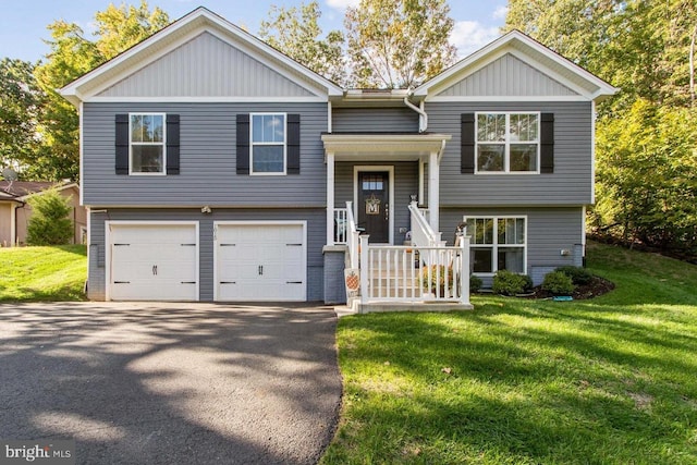 raised ranch with a garage, aphalt driveway, and a front lawn