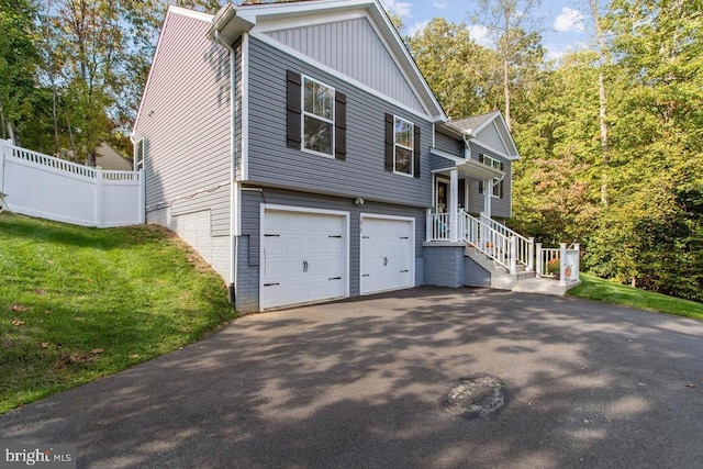 view of front of home with aphalt driveway, an attached garage, fence, and a front yard