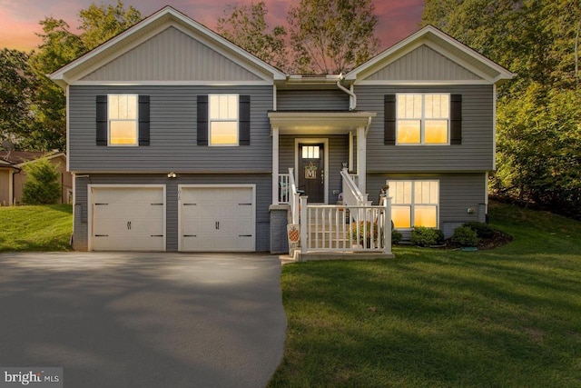 raised ranch with an attached garage, driveway, and a front lawn