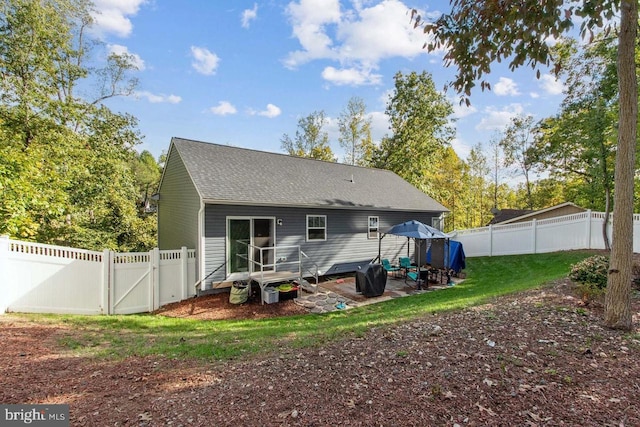 back of house featuring a fenced backyard, a shingled roof, a lawn, a gate, and a patio area