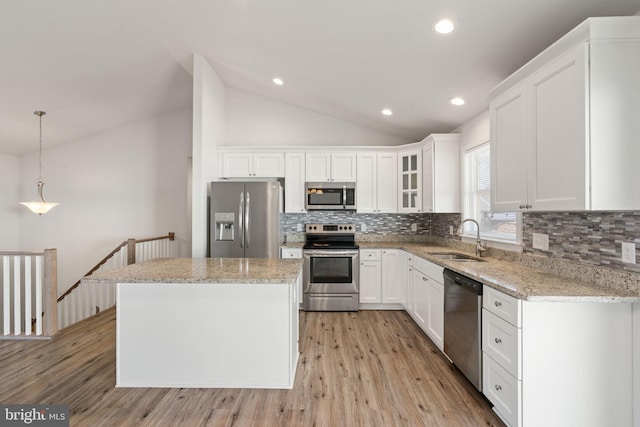 kitchen with a kitchen island, vaulted ceiling, stainless steel appliances, white cabinetry, and a sink