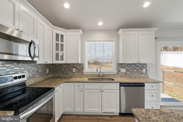 kitchen featuring appliances with stainless steel finishes, backsplash, a sink, and white cabinetry