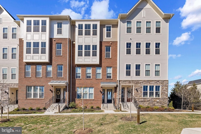 townhome / multi-family property featuring brick siding and a front yard