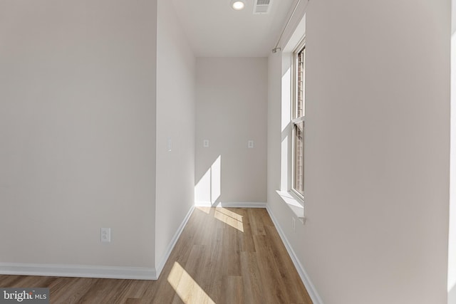 hallway with recessed lighting, wood finished floors, visible vents, and baseboards