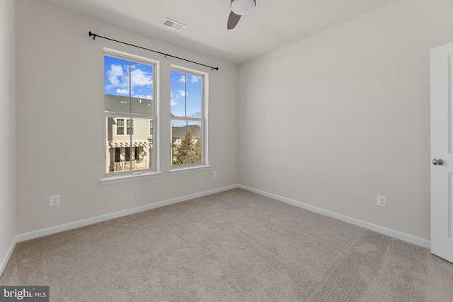 carpeted empty room featuring visible vents, ceiling fan, and baseboards