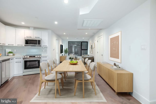 dining area featuring recessed lighting, baseboards, and light wood finished floors