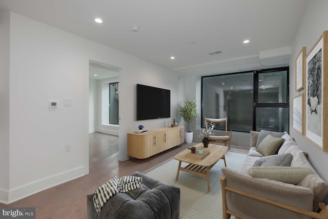 living area with recessed lighting, visible vents, baseboards, and wood finished floors