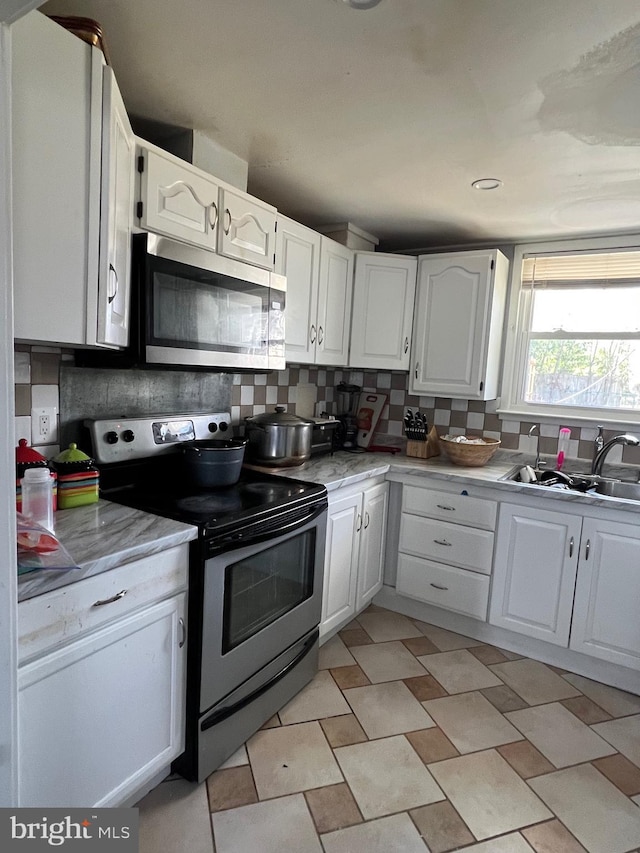 kitchen with stainless steel appliances, tasteful backsplash, and white cabinets