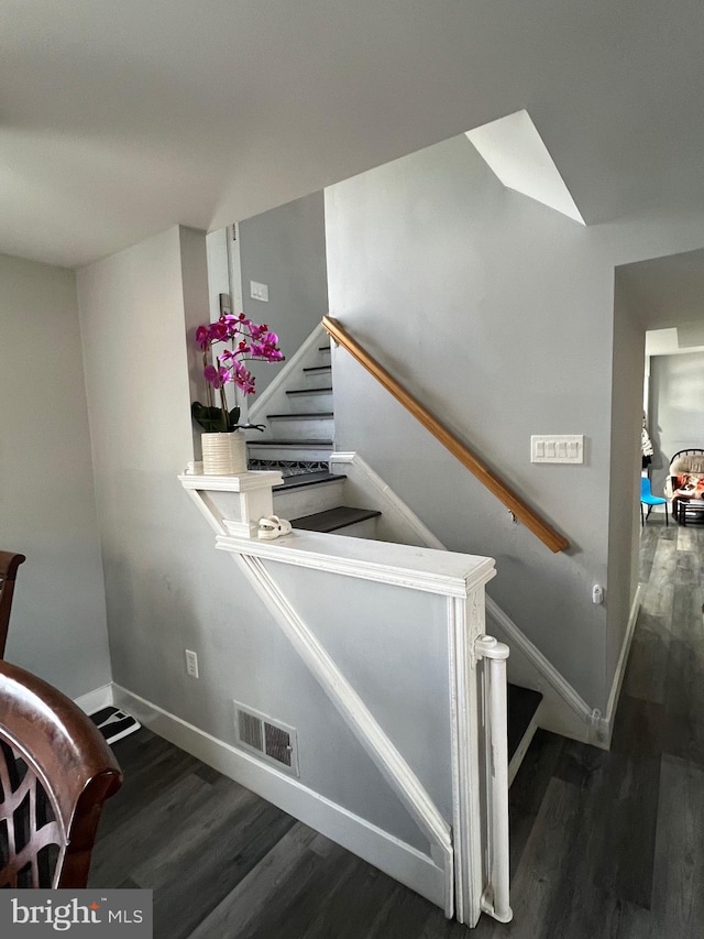 stairway with baseboards, visible vents, and wood finished floors