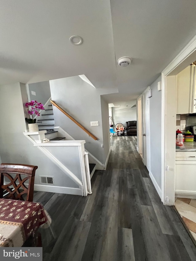 corridor featuring dark wood-style floors, baseboards, stairs, and visible vents