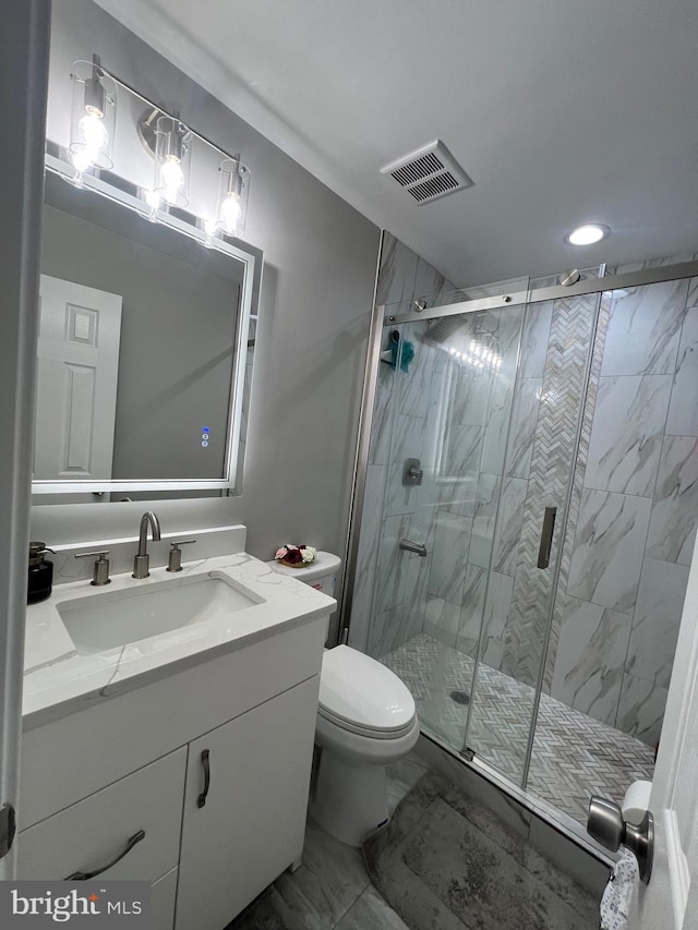 bathroom featuring toilet, vanity, visible vents, marble finish floor, and a stall shower