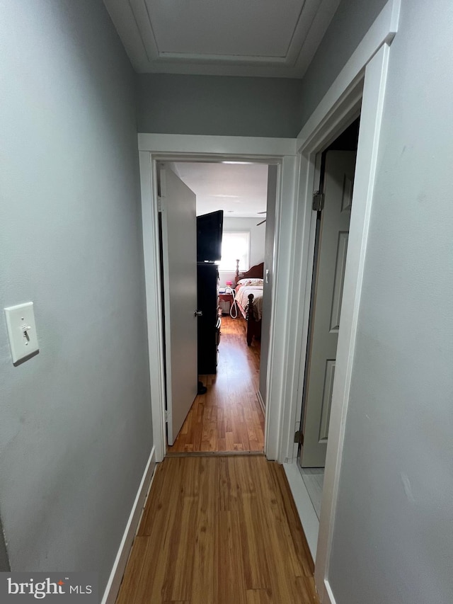 corridor with baseboards and wood finished floors