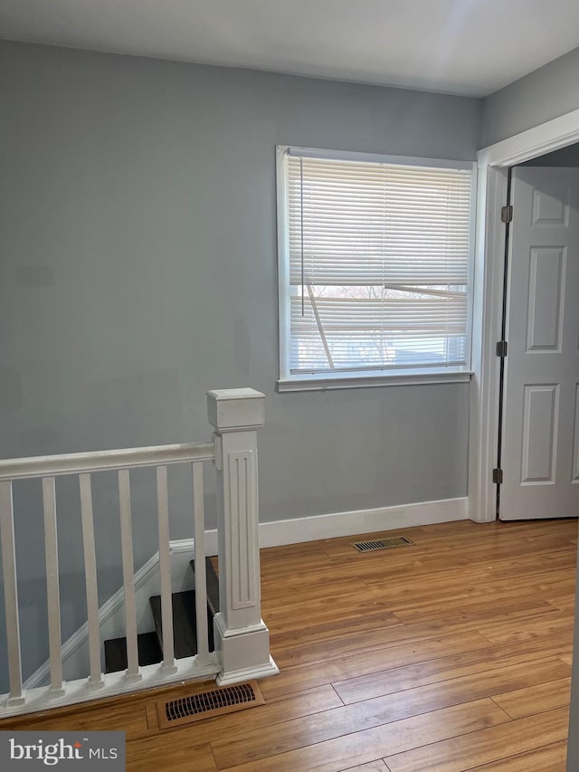 interior space featuring light wood-style flooring, an upstairs landing, visible vents, and baseboards