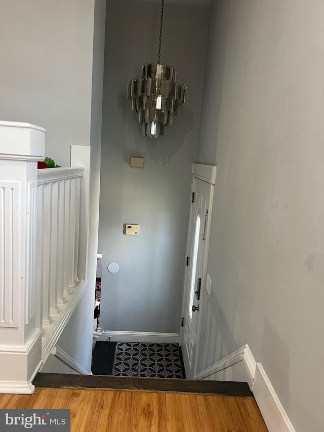 interior space with baseboards, wood finished floors, and an inviting chandelier