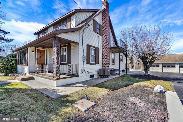 view of front of home with central AC unit, covered porch, and a chimney