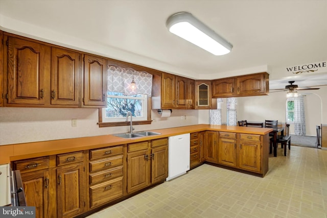 kitchen featuring a sink, brown cabinets, dishwasher, and a peninsula