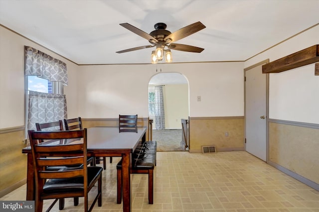 dining area with a wealth of natural light, a wainscoted wall, arched walkways, and visible vents