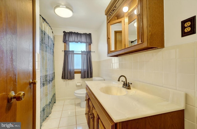 bathroom featuring tile patterned floors, toilet, tile walls, wainscoting, and vanity