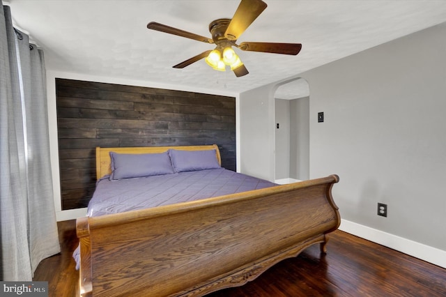 bedroom with ceiling fan, baseboards, arched walkways, and wood finished floors