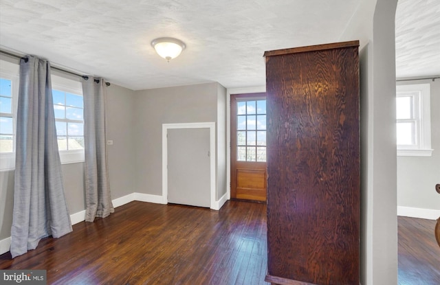 unfurnished room with dark wood finished floors and baseboards