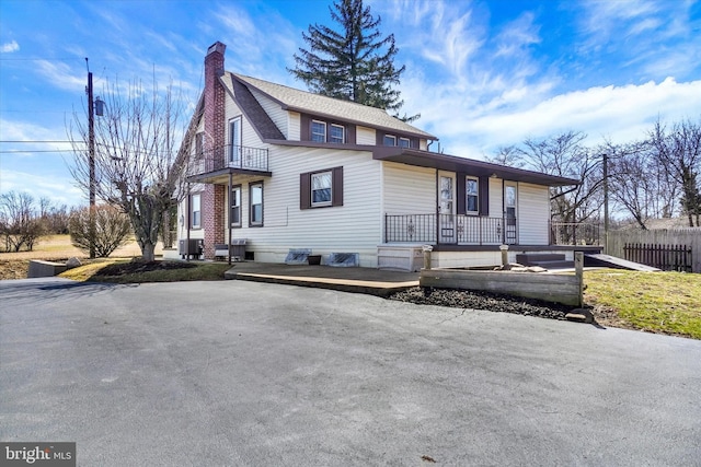 view of front of home with fence, covered porch, central AC, and a chimney